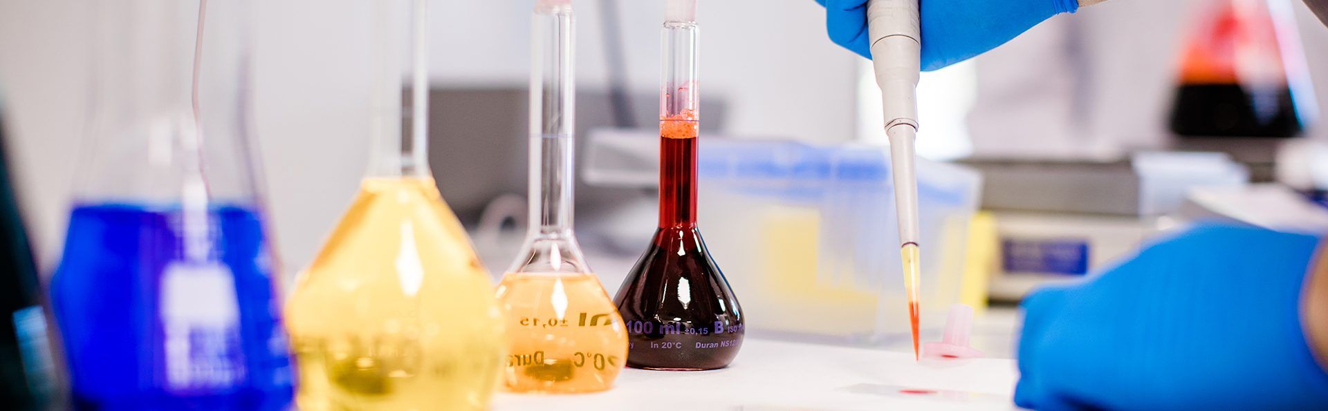 Pipette mit mehreren Glaskloben im Vordergrund